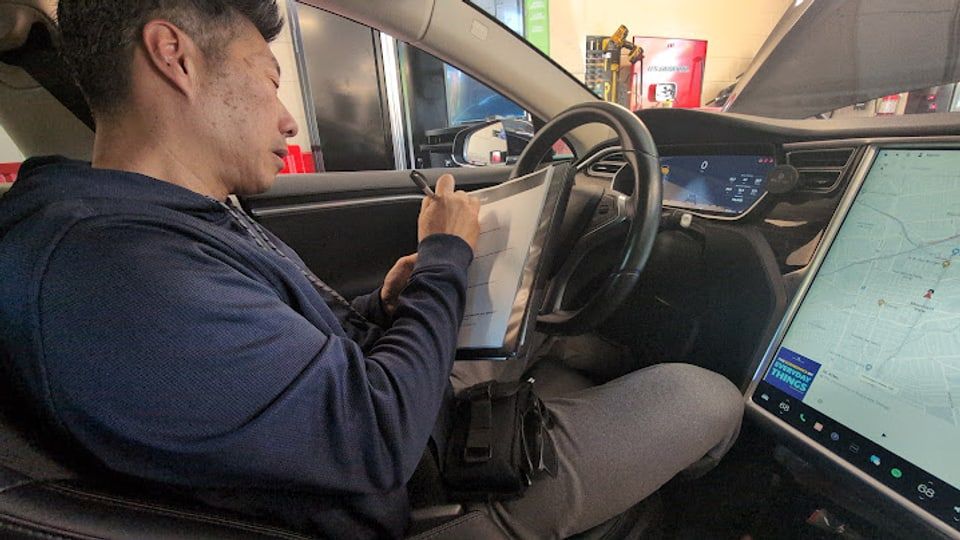 Man in a car's driver seat writing notes on a clipboard
