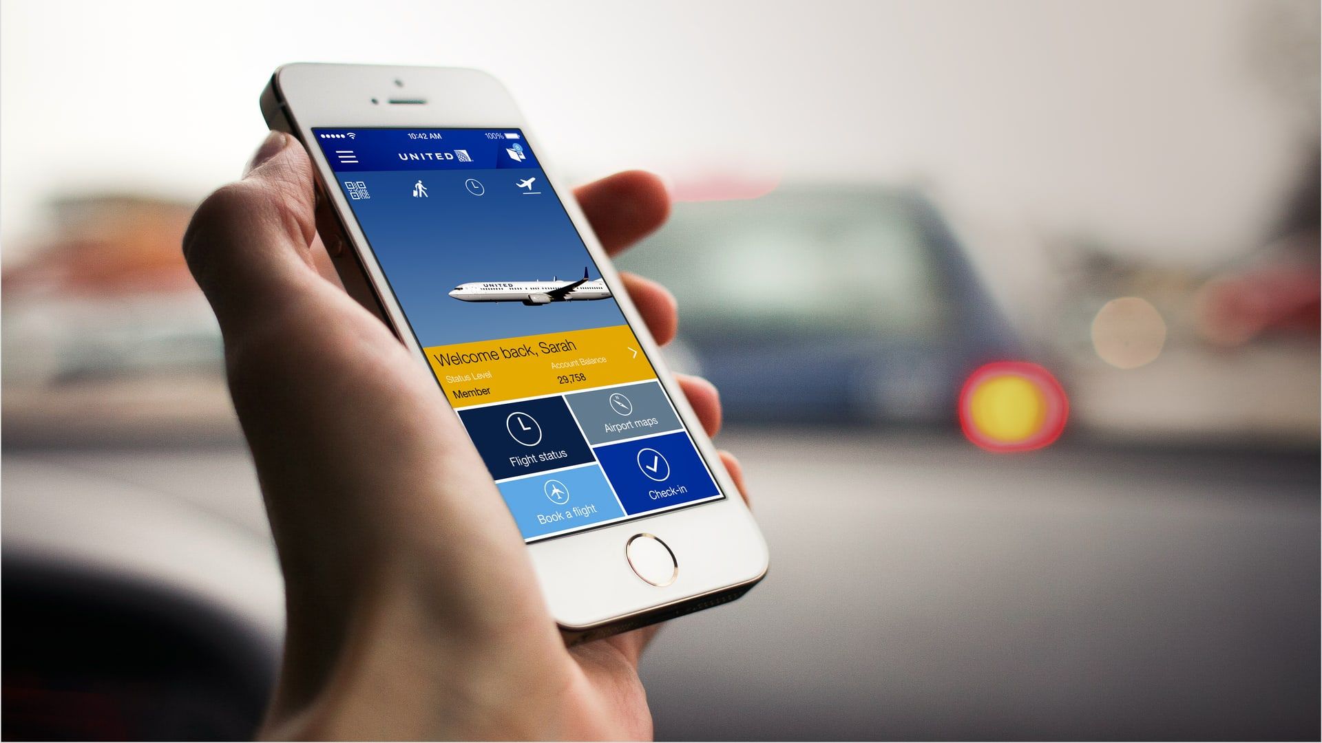 Hand holding a phone showing the United airline app home screen
